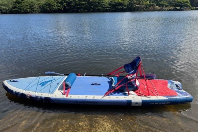 A couple enjoys paddleboarding at sunset on a serene Barcelona beach, capturing leisure and adventure.