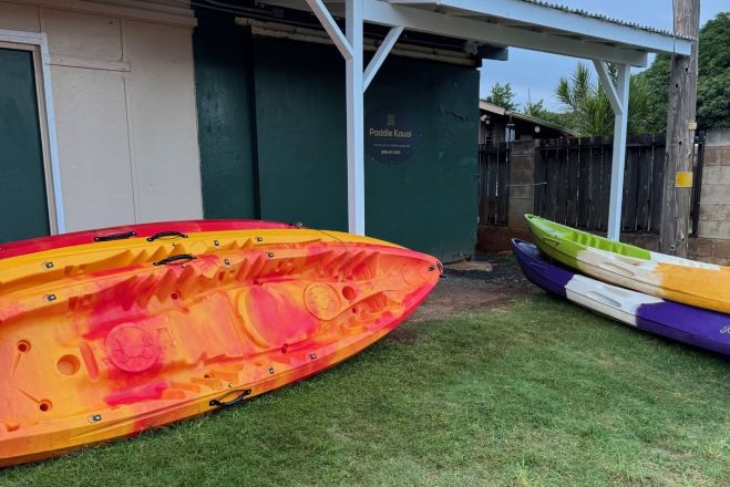 Vibrant kayaks stacked on a seaside rack at sunset in the Philippines, perfect for a serene adventure.